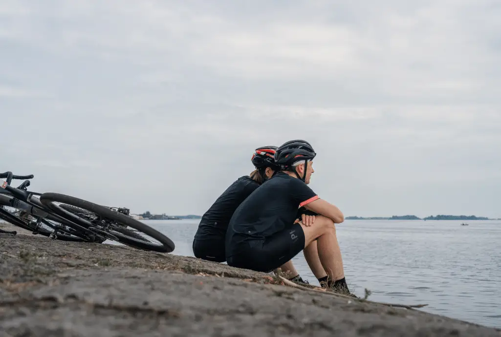 two cyclists sitting in front of water